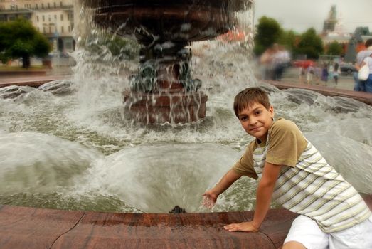 smiling caucasian boy by fountain in front of Bolshoy in Moscow, Russia