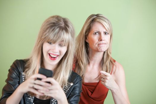Upset woman with laughing teen on cell phone