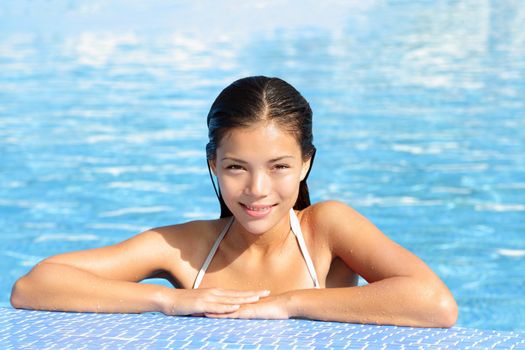 Woman beauty in pool on sunny vacation holiday resort. Gorgeous natural beautiful woman in swimming pool smiling happy. Multiracial young female beauty model in bikini outdoor. Mixed race Asian Chinese and Caucasian.