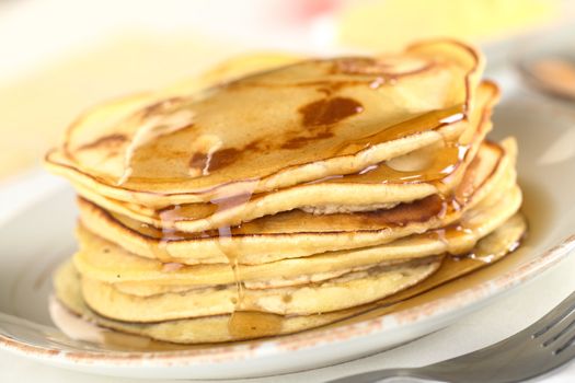 Fresh homemade pancakes with maple syrup (Selective Focus, Focus on the front of the upper three pancakes)