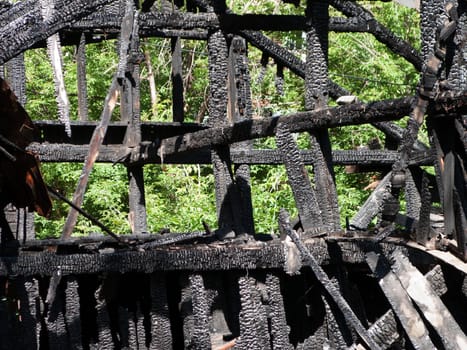 Ruined wood log house burnt by fire to black coal