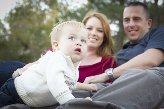 Cute Child Boy Looks Up to the Sky as Young Parents Smile.