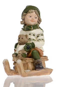 Miniature of child with bear dool on sleigh, on white reflective background.