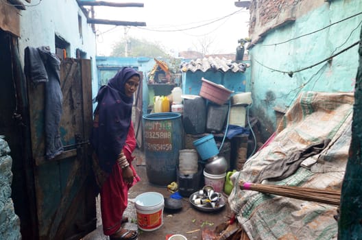 New Delhi,India-February 4, 2013:An unidentified woman in the courtyard of his house in the slum on February 4,2013 in New Delhi. 17 million residents do not have access to city water