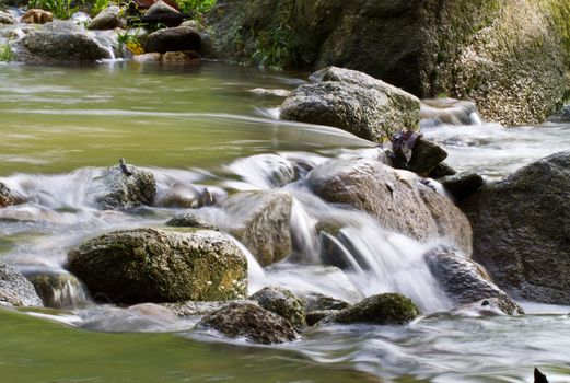 view of a  small river stream in the morning light with water running between rocks