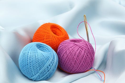 thread on blue silk background close up