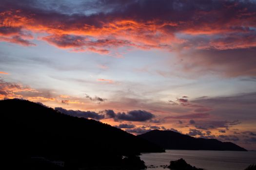 Sunset over the hills at Batu Ferringhi Penang Malaysia with silhouette of the hills and bay coastline