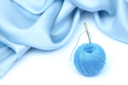 thread on blue silk isolated close up