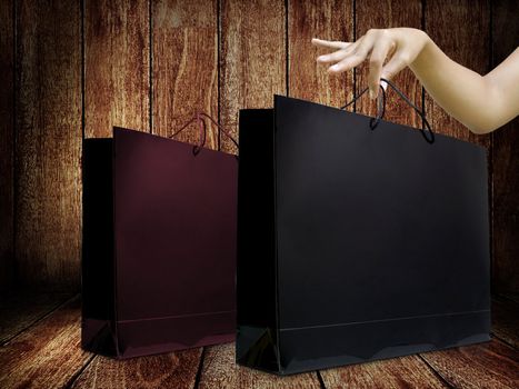 Glossy shopping bag in lady hand with wooden background