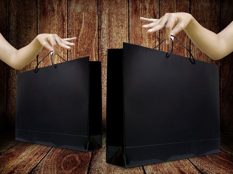 Glossy shopping bag in lady hand with wooden background