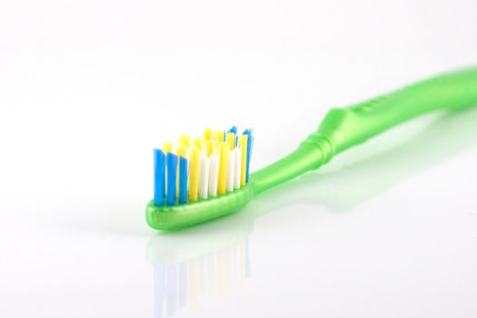 Tooth-brush with green handle over white. Shallow DOF