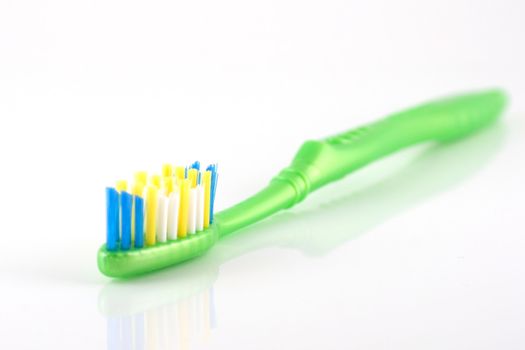 Tooth-brush with green handle over white. Shallow DOF