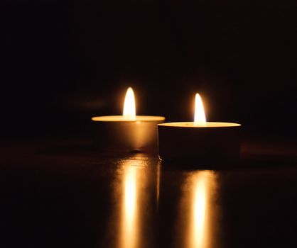Closeup of burning candles isolated in front of black background