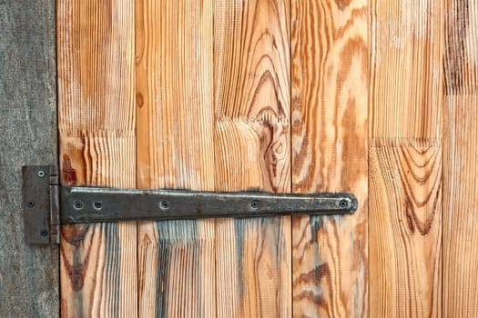 Fragment of wooden door with a large metal hinge