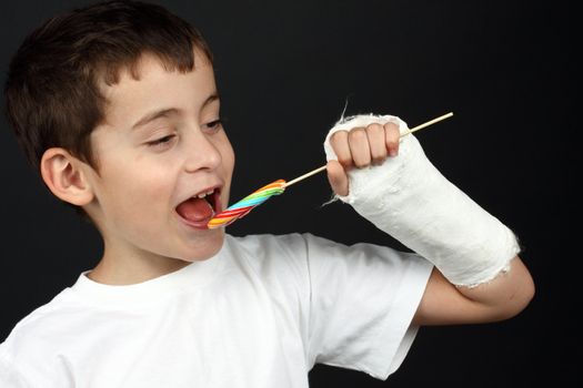 Boy with broken hand in cast, holding a lollipop 