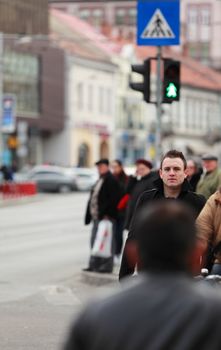 Image of a young businessman crossing a street in a city.Selective focus on the man with blur on the others people.