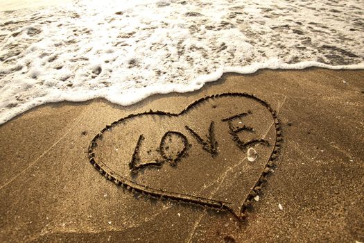 Love concept handwritten on sand