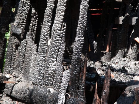 Ruined wood log house burnt by fire to black coal