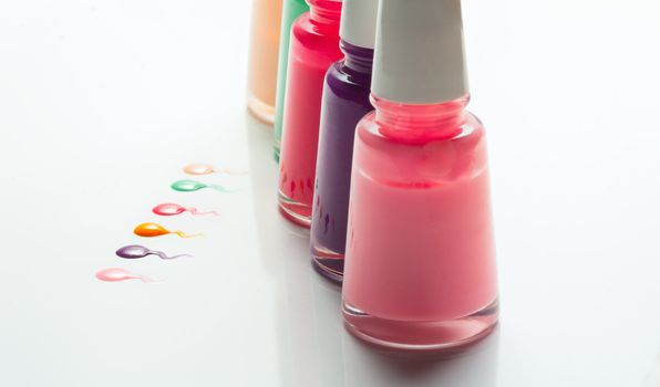 Bottles with spilled nail polish over white background