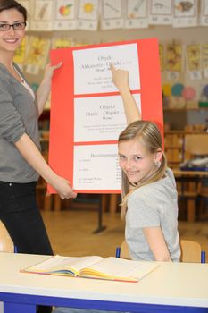 German teacher and pupil hours in the classroom to learn together and smiling
