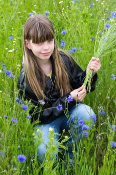 Girl with wild flowers cornflower in the meadow