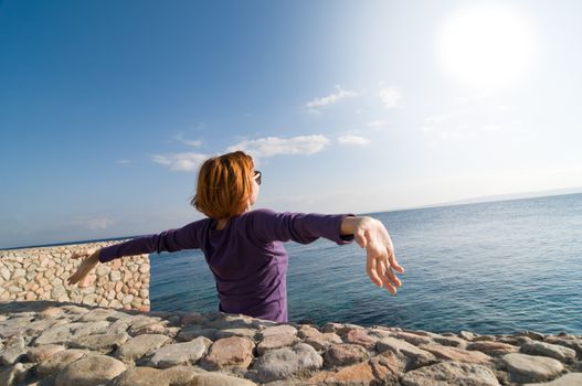 Happy young red woman with outstretched hands enjoying the sun