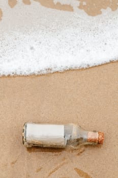 Brown paper in glass bottle lying on the beach.