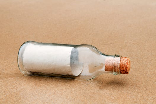 Brown paper in glass bottle lying on the beach.