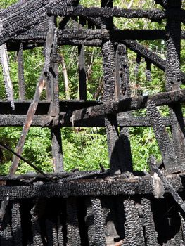 Ruined wood log house burnt by fire to black coal