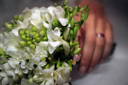 Wedding bouquet from white flowers in a hand of the bride