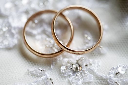 Wedding rings on a background of a wedding dress. 
