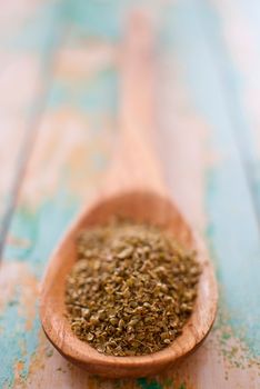 oregano spice in wooden spoon over wood background - selective focus