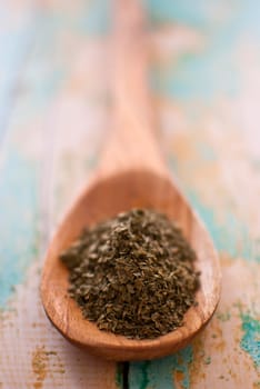 parsley spice in wooden spoon over wood background - selective focus