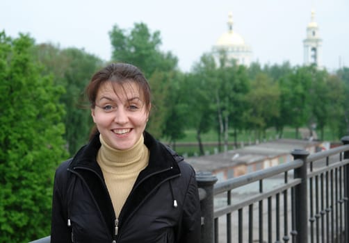 The smiling young woman against green park