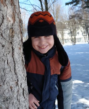 Winter. Smiling little boy near a tree.