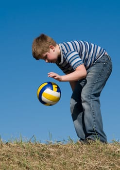 little boy with volleyball ball on a blue sky