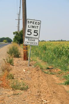 Speed limit road sign next to a road.
