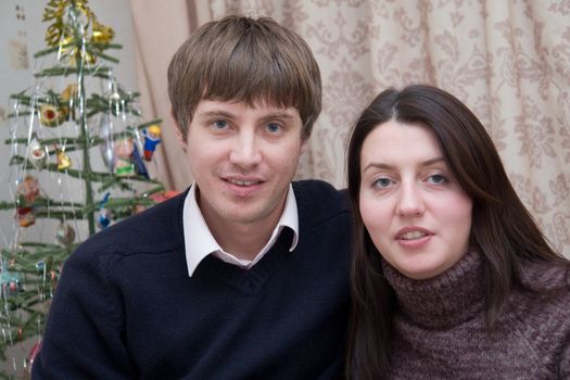 Married couple against a small New Year tree