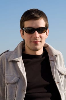 beautiful young man in black glasses against the sky