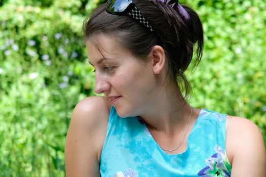 young beautiful woman in a profile against green foliage