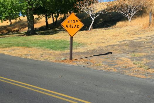 Stop ahead road sign next to a road.
