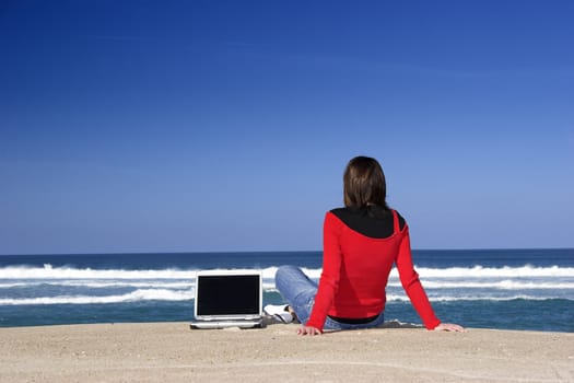 Woman working with a laptop on the beach