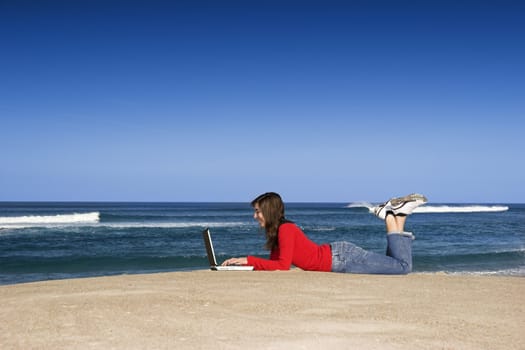 Woman working with a laptop on the beach