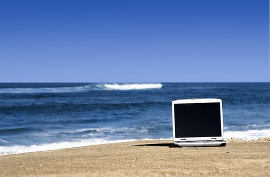 Open laptop on a beautiful beach with a great blue sky