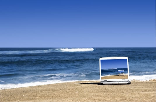 Open laptop on a beautiful beach with a great blue sky