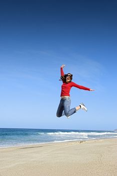 Young woman jumping on the beach and having fun