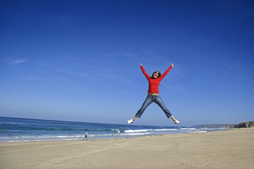 Young woman jumping on the beach and having fun