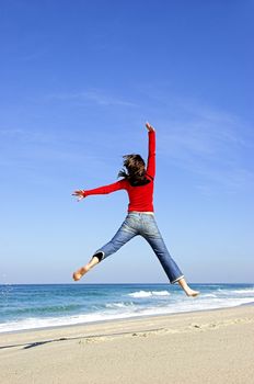 Young woman jumping on the beach and having fun