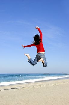 Young woman jumping on the beach and having fun