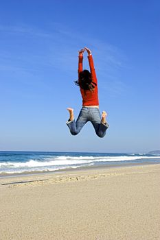 Young woman jumping on the beach and having fun